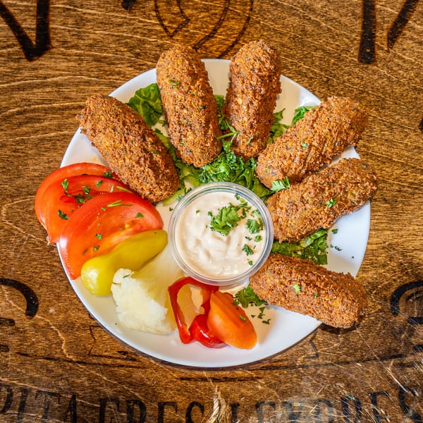 Pita Fresh Express falafel plate with tahini, sliced tomatoes, pickled vegetables, and fresh parsley.